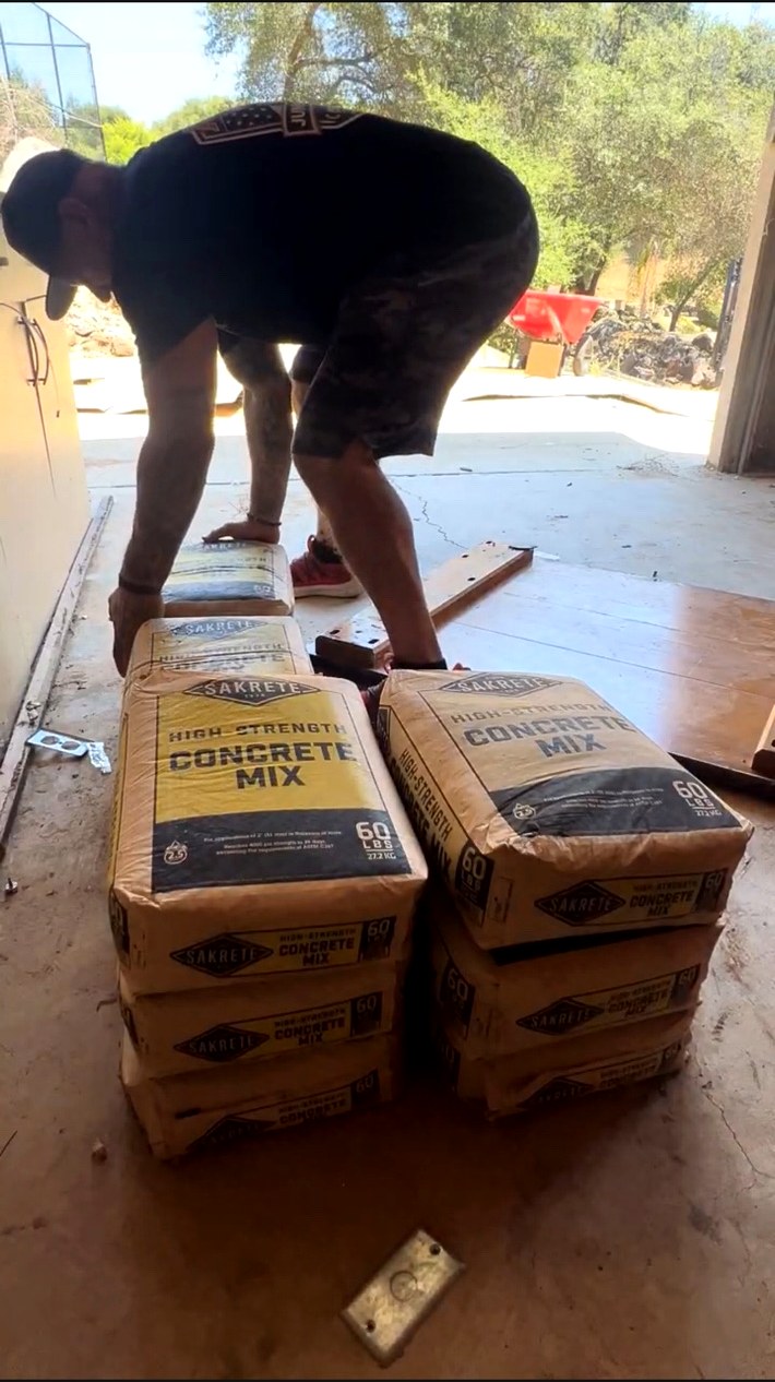 AMR Junk Removal crew member stacking heavy bags of concrete mix for removal from a garage
