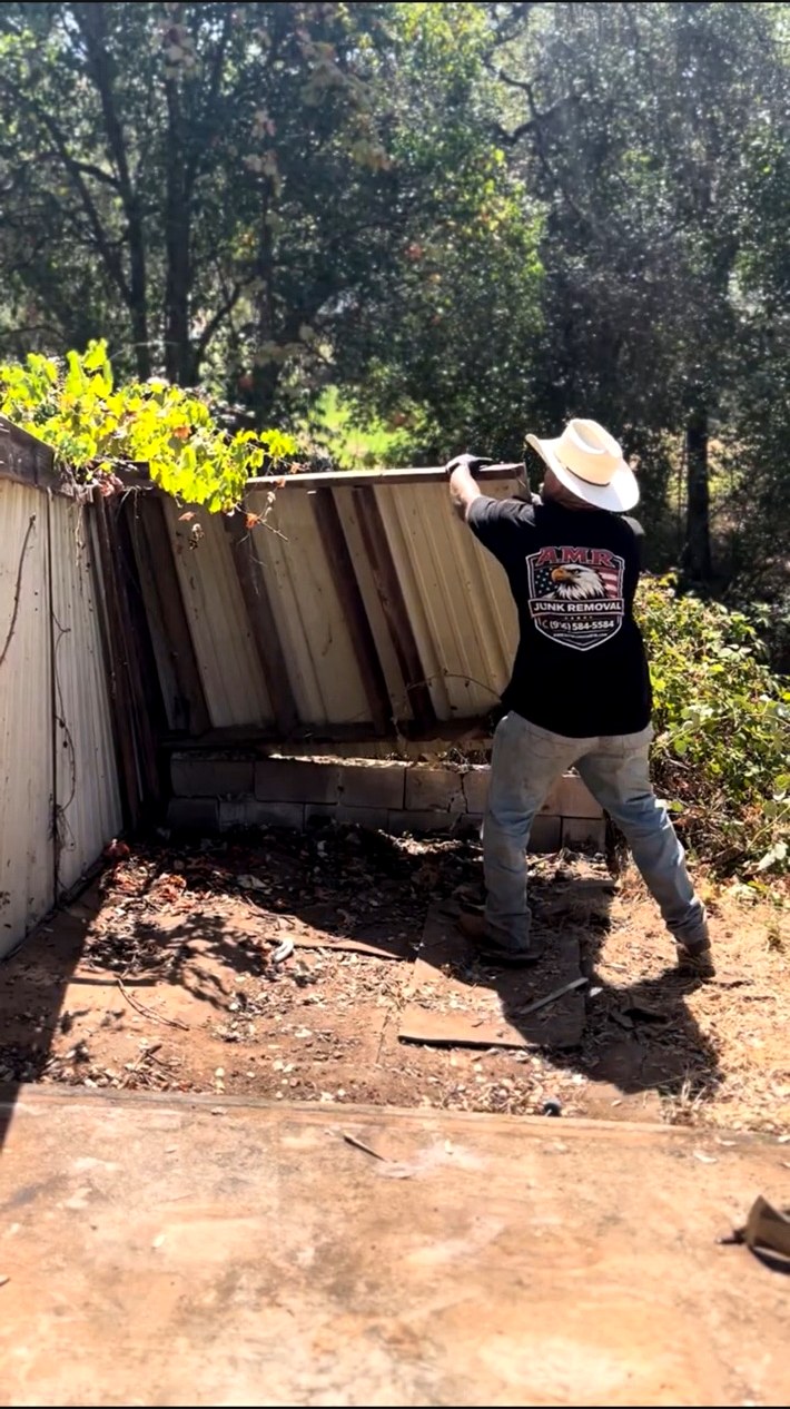 AMR Junk Removal crew tearing down an old wooden fence on a job site