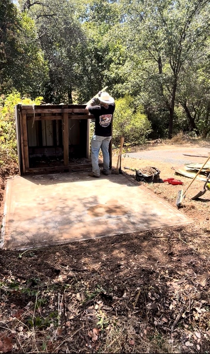 AMR Junk Removal crew member tearing down a small wood shed down to its concrete slab
